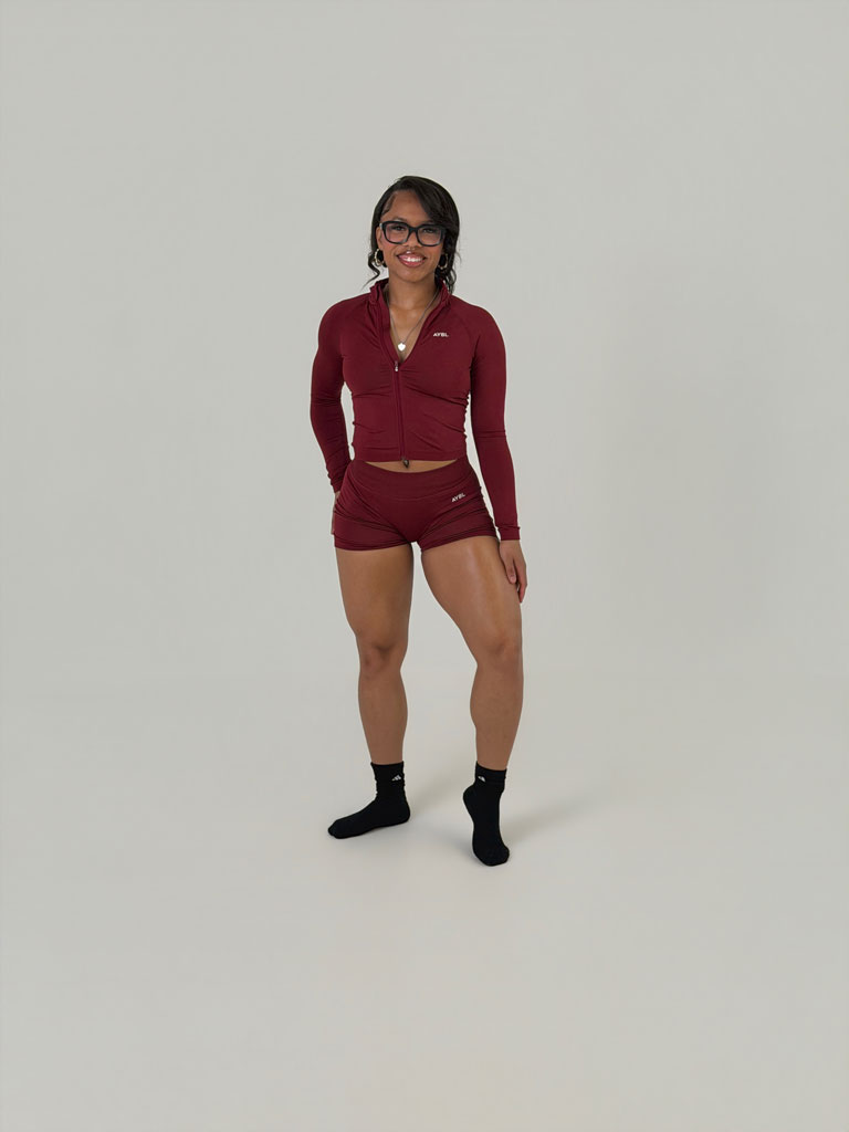Coach is posing in burgundy workout outfit.